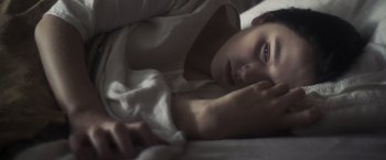 Movie still from “Carmilla” (2019), directed by Emily Harris – A woman laying in a bed with a white blanket; Extreme Close Up shot, High angle