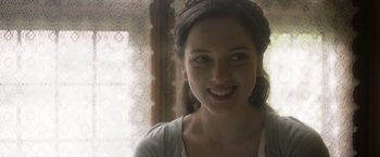 Movie still from “Carmilla” (2019), directed by Emily Harris – A young woman smiling for the camera in front of a window; Close Up shot, Over the shoulder angle