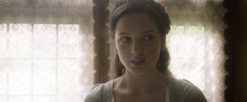 Movie still from “Carmilla” (2019), directed by Emily Harris – A young woman with long dark hair wearing a white shirt; Close Up shot, Over the shoulder angle