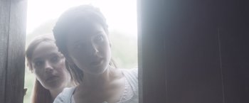 Movie still from “Carmilla” (2019), directed by Emily Harris – A woman looking out of a window at the light; Close Up shot, Over the shoulder angle