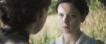 Movie still from “Carmilla” (2019), directed by Emily Harris – A woman looking at a man in a grassy field; Close Up shot, Over the shoulder angle