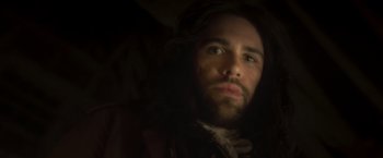 Movie still from “Carmilla” (2019), directed by Emily Harris – A man with long hair and a beard looking at the camera; Close Up shot, Low angle