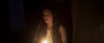 Movie still from “Carmilla” (2019), directed by Emily Harris – A woman is holding a candle in the dark; Medium shot, High angle