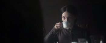 Movie still from “Carmilla” (2019), directed by Emily Harris – A woman is drinking a cup of coffee in the dark; Close Up shot, Over the shoulder angle