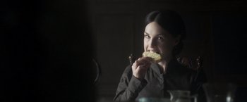 Movie still from “Carmilla” (2019), directed by Emily Harris – A woman is eating a piece of bread; Close Up shot, Over the shoulder angle