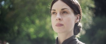 Movie still from “Carmilla” (2019), directed by Emily Harris – A woman's face in front of trees; Close Up shot, Low angle