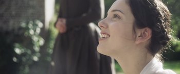 Movie still from “Carmilla” (2019), directed by Emily Harris – A person smiling with a person in the background; Close Up shot, Over the shoulder angle