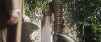 Movie still from “Carmilla” (2019), directed by Emily Harris – A woman standing next to a brick wall with a dog; Medium shot, Low angle