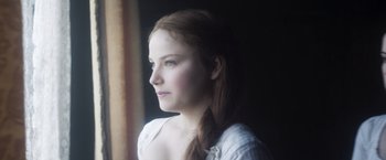Movie still from “Carmilla” (2019), directed by Emily Harris – A woman with long red hair is looking out a window; Close Up shot, Low angle