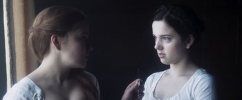 Movie still from “Carmilla” (2019), directed by Emily Harris – A woman is holding a needle in her hand while another woman looks on; Close Up shot, Over the shoulder angle