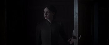 Movie still from “Carmilla” (2019), directed by Emily Harris – A woman holding a knife standing in a dark room; Medium shot, Low angle