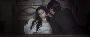 Movie still from “Carmilla” (2019), directed by Emily Harris – A woman putting a necklace on a young girl's mouth; Close Up shot, Over the shoulder angle