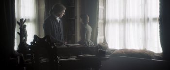 Movie still from “Carmilla” (2019), directed by Emily Harris – A man and a woman are standing in front of a window; Medium shot, Over the shoulder angle