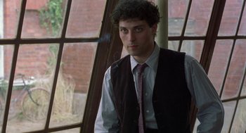 Movie still from “Carrington” (1995), directed by Christopher Hampton – A man in a vest and tie standing in front of a window; Close Up shot, Low angle