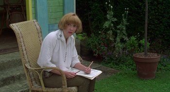 Movie still from “Carrington” (1995), directed by Christopher Hampton – A woman sitting in a chair writing on a piece of paper; Medium shot, Low angle