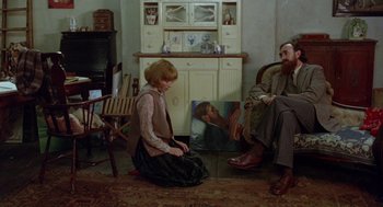 Movie still from “Carrington” (1995), directed by Christopher Hampton – A woman sitting on the ground in front of a painting; Medium shot, High angle
