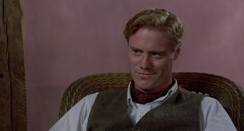 Movie still from “Carrington” (1995), directed by Christopher Hampton – A man sitting in a chair wearing a vest and a tie; Close Up shot, Over the shoulder angle
