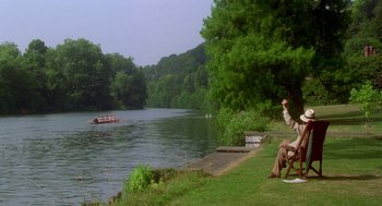 Movie still from “Carrington” (1995), directed by Christopher Hampton – Two people sitting on the grass near a body of water; Extreme Wide shot, High angle