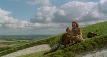 Movie still from “Carrington” (1995), directed by Christopher Hampton – A man and a woman sitting on top of a grassy hill; Wide shot, Low angle