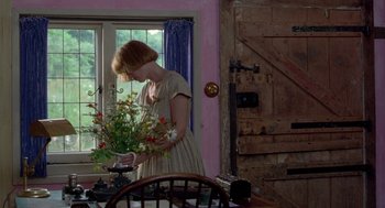 Movie still from “Carrington” (1995), directed by Christopher Hampton – A woman standing in front of a table holding a vase of flowers; Medium shot, High angle