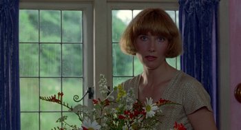 Movie still from “Carrington” (1995), directed by Christopher Hampton – A woman standing in front of a window holding a vase of flowers; Close Up shot, Low angle