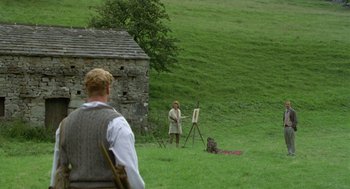 Movie still from “Carrington” (1995), directed by Christopher Hampton – A man standing in the grass with a painting; Wide shot, Over the shoulder angle