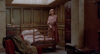 Movie still from “Carrington” (1995), directed by Christopher Hampton – A woman standing next to a bed in a room; Wide shot, High angle