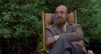 Movie still from “Carrington” (1995), directed by Christopher Hampton – A man sitting in a chair with his hands crossed; Medium shot, Over the shoulder angle