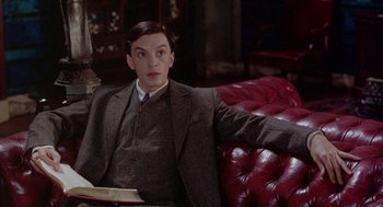 Movie still from “Carrington” (1995), directed by Christopher Hampton – A man sitting on top of a red leather couch; Medium shot, High angle