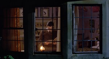Movie still from “Carrington” (1995), directed by Christopher Hampton – A man standing in front of an open window at night; Medium shot, High angle