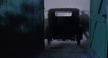 Movie still from “Carrington” (1995), directed by Christopher Hampton – An old car is parked in a garage in the fog; Wide shot, Low angle