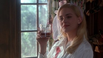 Movie still from “Cast a Deadly Spell” (1991), directed by Martin Campbell – A woman holding a wine glass in her right hand; Close Up shot, Over the shoulder angle