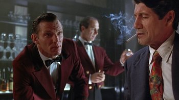 Movie still from “Cast a Deadly Spell” (1991), directed by Martin Campbell – A group of men smoking cigarettes in a room; Medium shot, Low angle