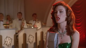 Movie still from “Cast a Deadly Spell” (1991), directed by Martin Campbell – A woman in a green dress singing into a microphone in front of a band; Close Up shot, Over the shoulder angle