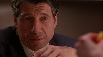Movie still from “Cast a Deadly Spell” (1991), directed by Martin Campbell – A person wearing a suit and tie; Close Up shot, Over the shoulder angle