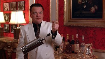 Movie still from “Cast a Deadly Spell” (1991), directed by Martin Campbell – A man in a white suit holding a silver bottle; Medium shot, Low angle