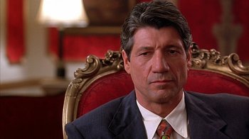 Movie still from “Cast a Deadly Spell” (1991), directed by Martin Campbell – A person sitting in a chair wearing a suit; Close Up shot, Over the shoulder angle