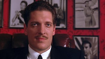 Movie still from “Cast a Deadly Spell” (1991), directed by Martin Campbell – A person wearing a suit and tie; Close Up shot, Low angle