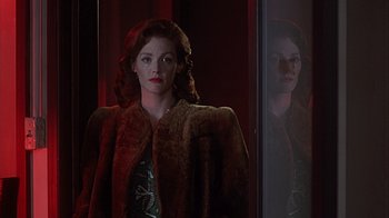 Movie still from “Cast a Deadly Spell” (1991), directed by Martin Campbell – A woman standing in front of a mirror in a dark room; Medium shot, Over the shoulder angle