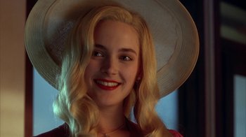 Movie still from “Cast a Deadly Spell” (1991), directed by Martin Campbell – A woman with blonde hair wearing a white hat; Close Up shot, Over the shoulder angle