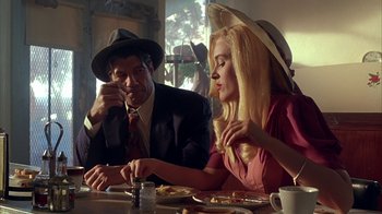 Movie still from “Cast a Deadly Spell” (1991), directed by Martin Campbell – A man and a woman sitting at a dinner table; Medium shot, Over the shoulder angle