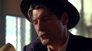 Movie still from “Cast a Deadly Spell” (1991), directed by Martin Campbell – A person wearing a hat and smoking a cigarette; Close Up shot, Low angle