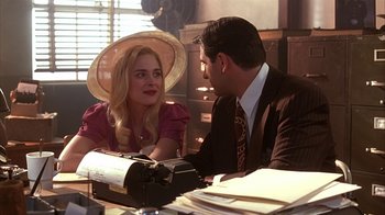 Movie still from “Cast a Deadly Spell” (1991), directed by Martin Campbell – A man and a woman sitting in front of a typewriter; Medium shot, Over the shoulder angle