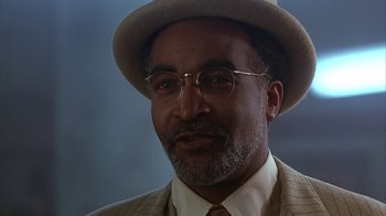 Movie still from “Cast a Deadly Spell” (1991), directed by Martin Campbell – An older man wearing a hat and glasses; Close Up shot, Low angle
