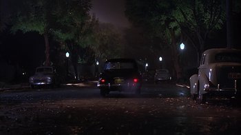Movie still from “Cast a Deadly Spell” (1991), directed by Martin Campbell – A car is driving down the street at night; Extreme Wide shot, High angle