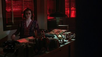 Movie still from “Cast a Deadly Spell” (1991), directed by Martin Campbell – A woman sitting in front of a mirror in a dark room; Medium shot, Over the shoulder angle