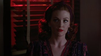 Movie still from “Cast a Deadly Spell” (1991), directed by Martin Campbell – A woman with red hair wearing a purple and red dress; Close Up shot, Over the shoulder angle