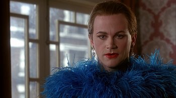 Movie still from “Cast a Deadly Spell” (1991), directed by Martin Campbell – A woman in a blue dress with a blue feather boa; Close Up shot, Over the shoulder angle
