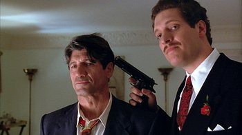 Movie still from “Cast a Deadly Spell” (1991), directed by Martin Campbell – Two men in suits and ties with a gun in their head; Close Up shot, Low angle