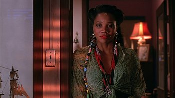 Movie still from “Cast a Deadly Spell” (1991), directed by Martin Campbell – A woman with long dangling earrings standing next to a door; Close Up shot, Low angle